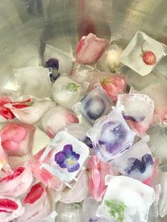 some ice cubes with flowers in them are sitting in a metal bowl filled with water