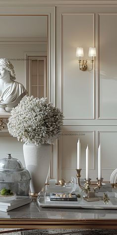 a table topped with white flowers and candles next to a busturine on the wall