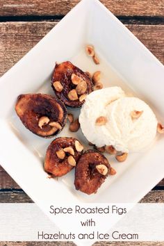 some food is on a white plate with nuts and ice cream in the middle that says spice roasted figs with hazelnuts and ice cream