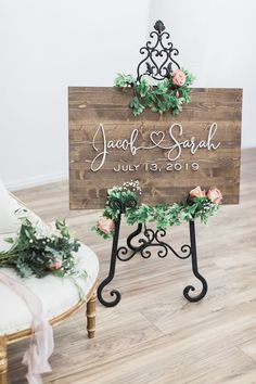 a wooden sign with greenery and flowers on it