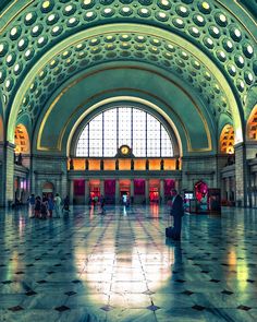 the inside of a train station with lots of windows and people standing in it at night