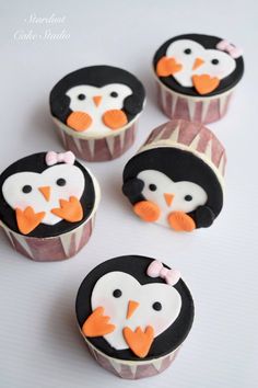 four cupcakes with penguins on them sitting next to each other