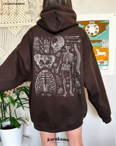 "This Unisex hooded sweatshirt features a vintage set of human bones, skeleton, insects & botanicals. It is the perfect sweater for anatomists, scientists, emergency physicians & more! Make sure to check out the other garment options below :) » O P T I O N S « ‣ Crewneck: https://www.etsy.com/listing/1058925206 » A B O U T « ‣ This item is made to order using direct-to-garment (DTG) printing technology. This digital process involves the printer inks being jetted or sprayed onto the textile by a Clothing For School, Anatomy Sweater, Skeleton Bleach Sweatshirt, Skeleton Bleach Hoodie, Skeleton Sweatshirt Bleach, Dark Academia Science, Hoodies Skeleton, Brown Skeleton Hoodie, Skeleton Hoodie