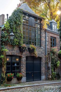 an old brick house with ivy growing on the windows and doors, along with potted plants