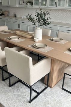 a dining room table with chairs and plates on top of it in front of cabinets