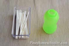 a plastic container filled with toothpicks next to a box of matchesticks