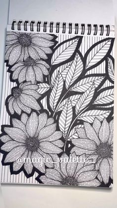 a spiral notebook with black and white flowers on it