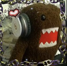 a brown teddy bear with red and white teeth has headphones in it's ears