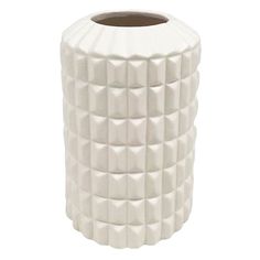 a white ceramic vase with geometric design on the front and sides, sitting on a white surface