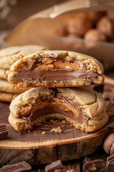 two cookies with chocolate and peanut butter are stacked on top of each other in front of some nuts