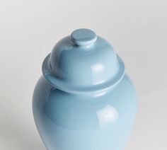 a blue vase with a lid sitting on a white surface