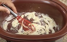 a person mixing food in a pot with a whisk