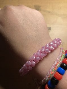 a close up of a person's hand wearing bracelets with beads on it