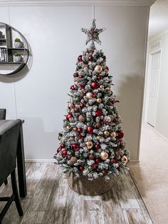 a decorated christmas tree with red and gold ornaments in a basket on the floor next to a dining room table