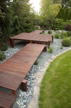 a wooden bench sitting on top of a lush green field next to a river filled with rocks