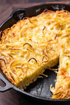 a cheesy dish is shown in a cast iron skillet on a wooden table