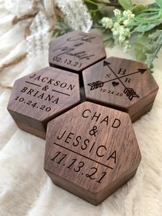 three wooden coasters with names and arrows on them, sitting next to some flowers