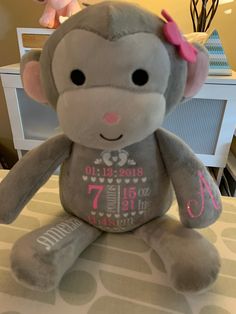 a gray stuffed monkey sitting on top of a bed next to a pink teddy bear