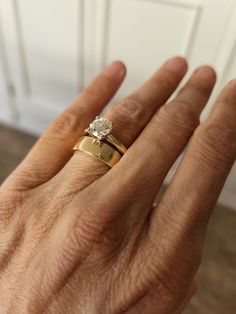 a person's hand with two gold rings on their fingers and one has a diamond in the middle