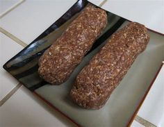 two loaves of bread sitting on top of a black and white plate next to a knife