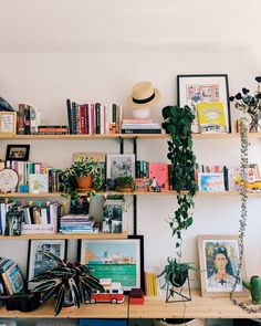 a living room filled with lots of books and plants next to a wall mounted shelf