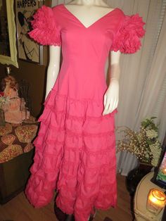 "Maybe 60's/70's lovely pink ruffle-listic dress, ankle-length, by Creaciones, in a size 7/C. Great Quinceanera celebration wear, with V-neck-off shouldered fitted bodice, huge ruffled 4 layered sleeves, and the skirt part is tapered at the waist, with and 8 layered ruffled skirt. The dress has a nylon back zipper closure, and in photo 6 & 7, is not zipped all the way to the top/back, because my mannequin is a slight too large for it. Dress is of cotton fabric, and is a little weighty from s Spring Party Vintage Dress With Ruffles, Spring Vintage Dress With Ruffles For Parties, Vintage Party Dress With Ruffle Hem, Spring Vintage Fashion Dress With Ruffles, Retro Pink Dresses With Ruffles, Spring Vintage Fashion Ruffled Dress, Retro Pink Ruffled Dresses, Pink Retro Dresses With Ruffles, Pink Retro Dress With Ruffles