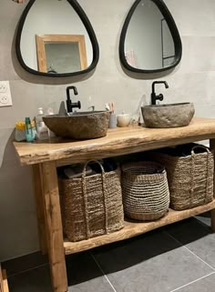 two sinks in a bathroom with baskets under them and mirrors on the wall behind them