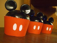 three mickey mouse cupcakes sitting on top of a wooden table