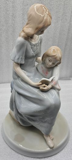 a ceramic figurine of a woman holding a child on top of a plate