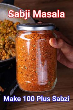 a person holding a jar filled with food next to a frying pan on top of a wooden table