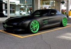 a black car with green rims parked in front of a building