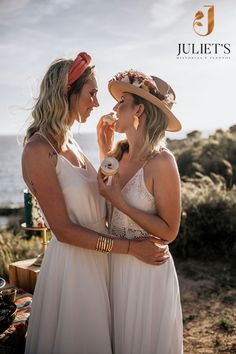 two beautiful women standing next to each other in front of the ocean and one is eating an ice cream cone