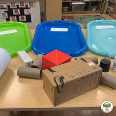 several different colored plates and containers on a table with cardboard boxes around them, including one for the lid