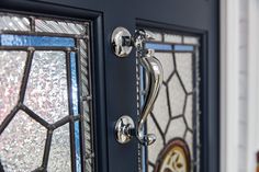 a close up of a door handle on a glass front door with stained glass panels