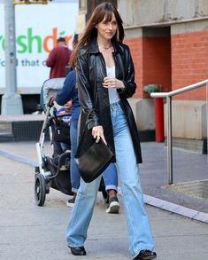 a woman is walking down the street with her hand in her pocket and holding a purse