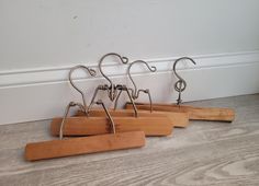 four metal hooks on wood stand in front of a white wall and hardwood flooring