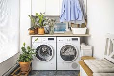 a washer and dryer sitting in a room next to a window with plants on it