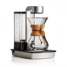 a coffee maker with a glass carafe and wooden handle on the top, sitting on a white surface