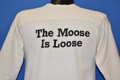 "Chest 17.5 in. Length 23.5 in. Tag Says: Artex, Medium, 100% cotton, Made in USA This shirt is for Moosehead Beer, made by Canada's oldest independent brewery which was founded in 1867. The back of this shirt includes the phrase \"the moose is loose\". Comments: Fits like a modern unisex adult small. This shirt is off white. 3/4 sleeves. Repair near the bottom. Double sided print. 21-03-108881" Cotton Band Merch Tops With Lettering, White Cotton Shirt With Lettering, Moosehead Beer, Cape Canaveral Florida, Red Cardigan Sweater, Red Cardigan, Beer Label, Philadelphia Pa, Moose