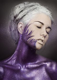 a woman with white hair and purple paint on her face is posing for the camera