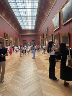 many people are standing in an art museum looking at paintings on the walls and ceiling