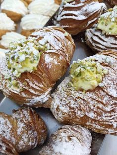 many different types of pastries on display in a store window with powdered sugar sprinkled on them