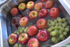 apples and grapes are being washed in a sink