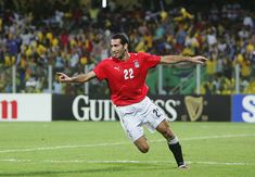 a soccer player in action on the field during a game with fans watching from the stands