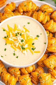 a white plate topped with lots of food next to a cup of dip and some pretzels