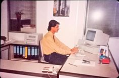 a man sitting at a desk in front of a computer monitor with a keyboard and mouse