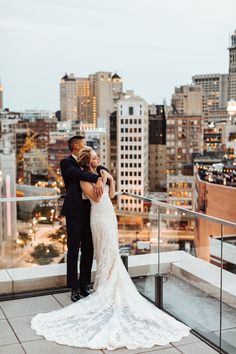 a bride and groom standing on top of a building in front of the city skyline