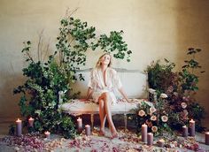 a woman sitting on a bench surrounded by flowers and candles