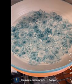 a white bowl with blue flowers in it on top of a shelf next to a wire rack