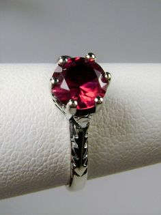 Simulated Red Ruby Ring Wedding #D22 This is a Victorian Era solitaire ring. This lovely sterling silver wedding solitaire has an approximately .5 carat simulated red ruby gemstone. This full cut flawless gemstone is 6mm (1/4") in diameter. The inside of the band is marked 925 for sterling silver. Notice the beautiful crown design of the silver filigree setting and the etched band. This is a lovely rendition of an Antique filigree ring. Classically fashioned, this ring is a vintage wedding style Red Ruby Ring, Antique Filigree, Victorian Wedding, Crown Design, Vintage Style Wedding, Filigree Ring, Ruby Gemstone, Engraved Items, Red Ruby